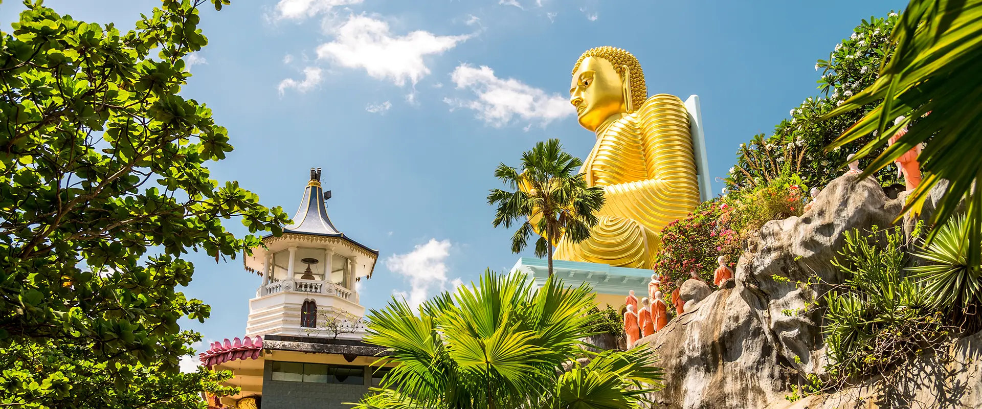 View of the massive seated Golden Buddha statue at the base of the Dambulla Cave Temple hill, a highly visible landmark on the Sigiriya Day Tour from Galle.