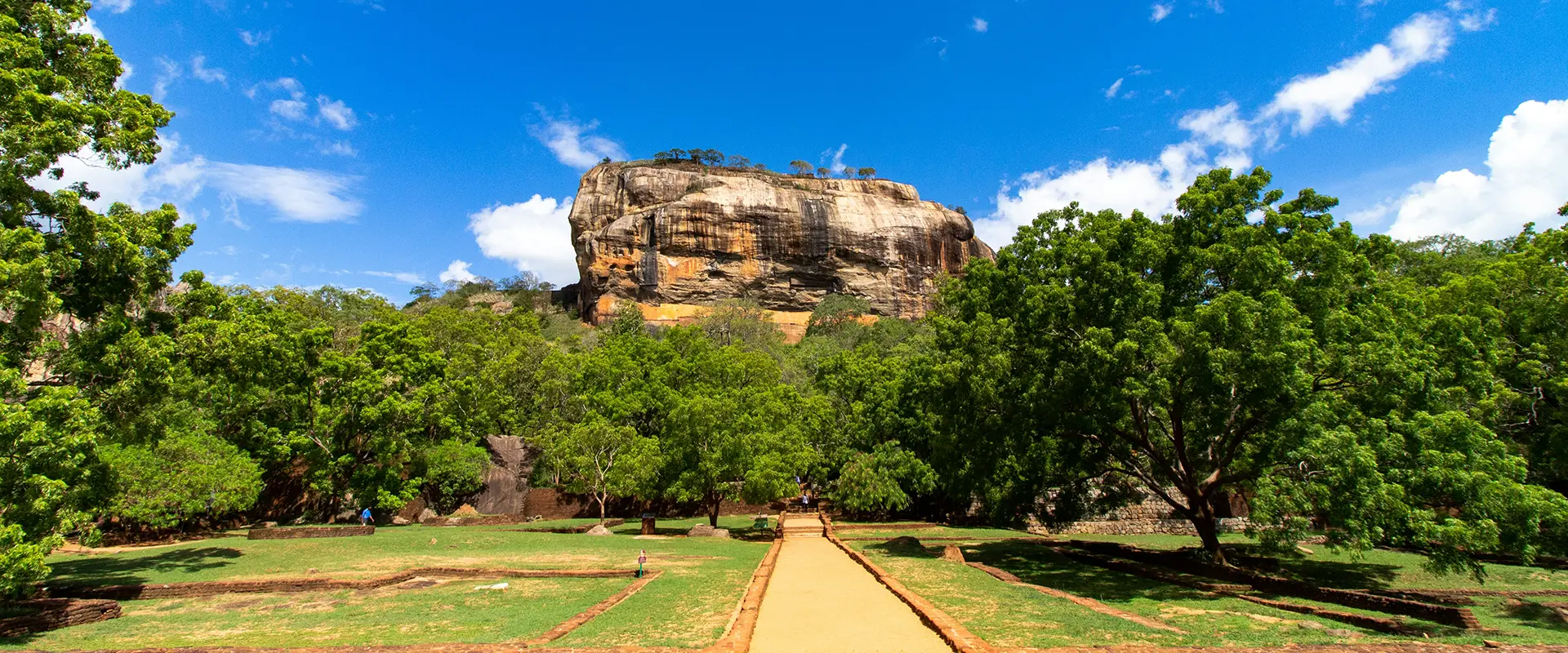 View of the ancient water gardens and path leading to the massive Sigiriya Lion Rock fortress, a key stop on the Sigiriya Day Tour from Galle.